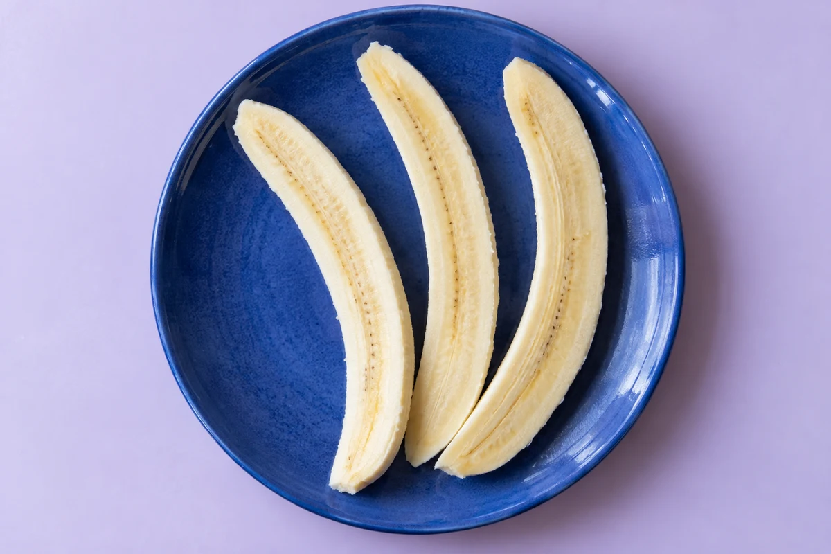 Three long peeled banana spears on a blue plate. AI-generated illustration.